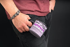 closeup of a charcoal colored coffee mug with the MMOG field background image in posterized white and fuscia.